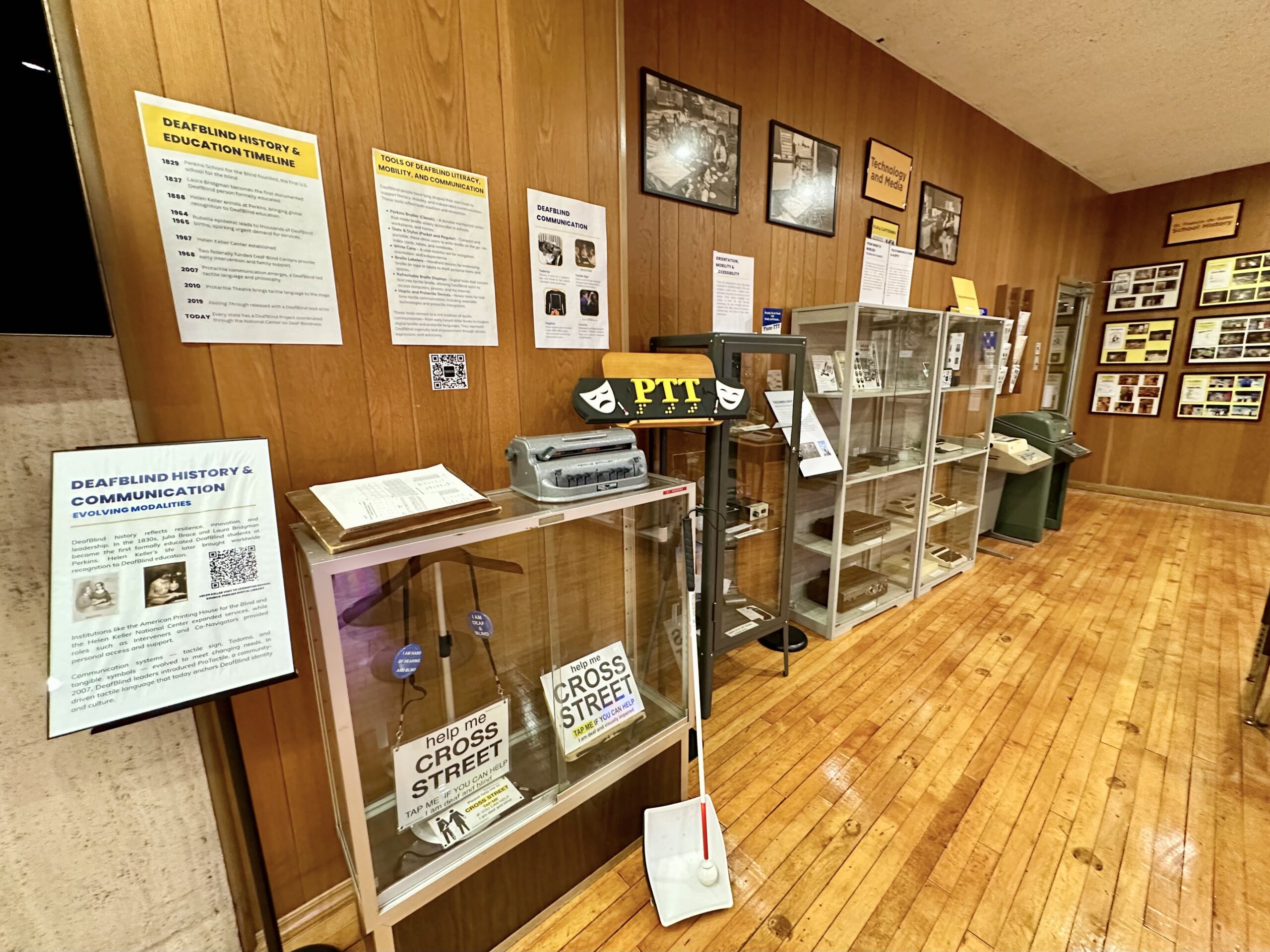 Museum exhibit area with a glass case of objects in the foreground and interpretive panels mounted along the wall.