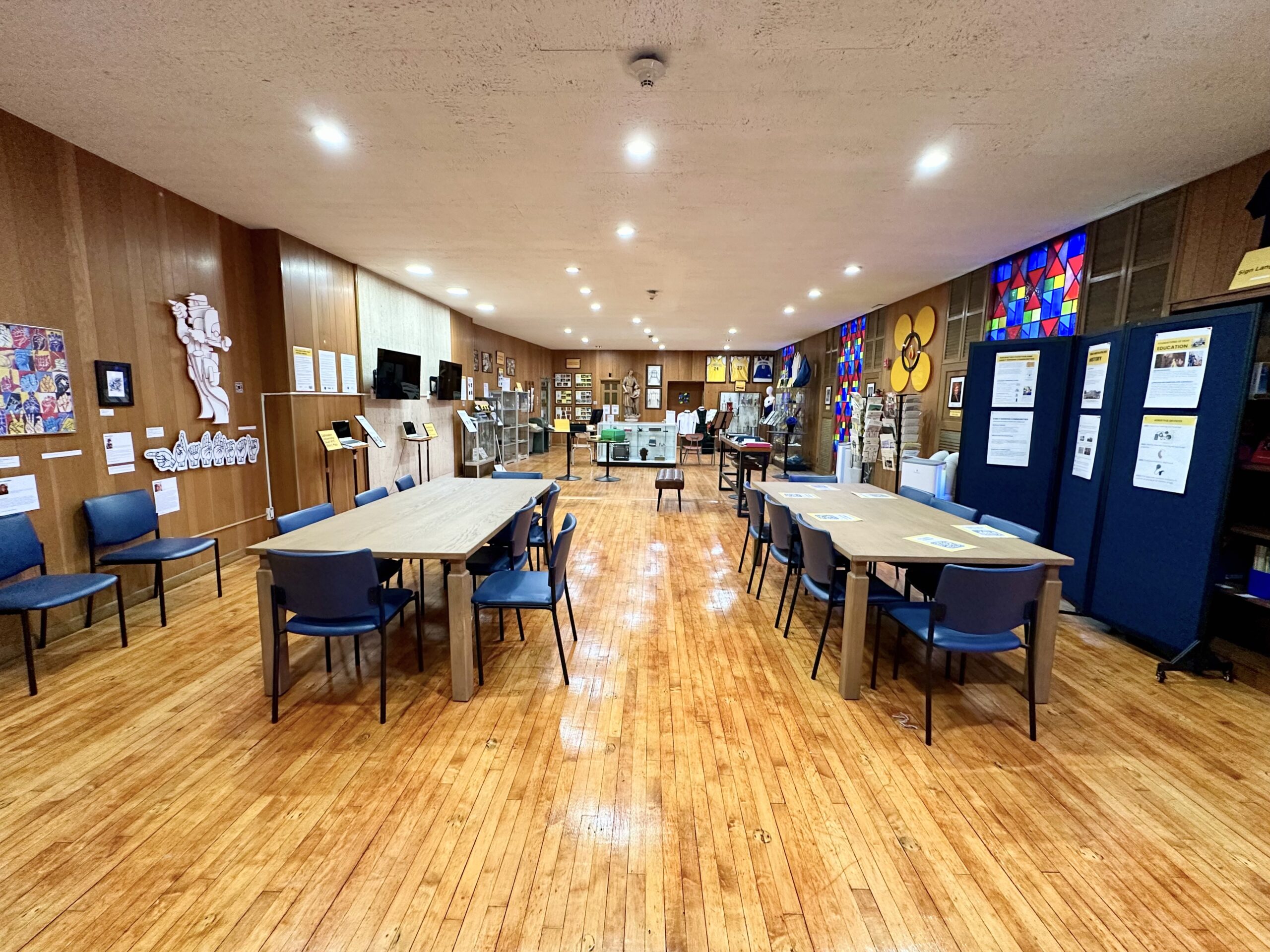 Long museum and research room with tables and chairs set out for visitors, display cases along both walls.