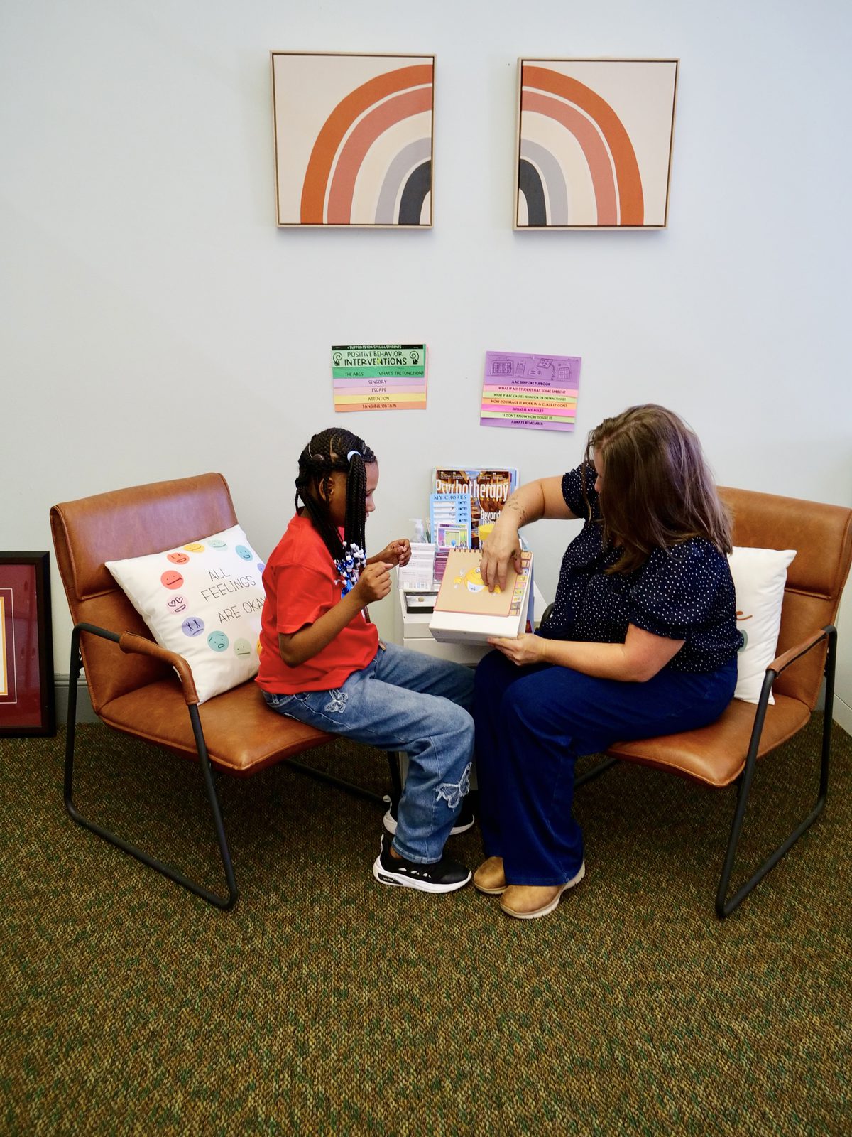 A wider view of the same counseling session, the counselor and student signing to each other in the counseling room.